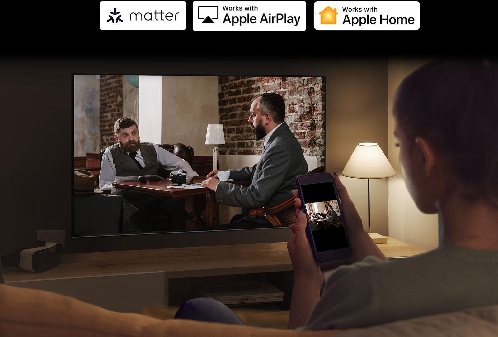 زنی در اتاقی تاریک نشان داده می شود که در حال تماشای ویدیویی از تلفن خود در تلویزیون از طریق آینه کردن است.