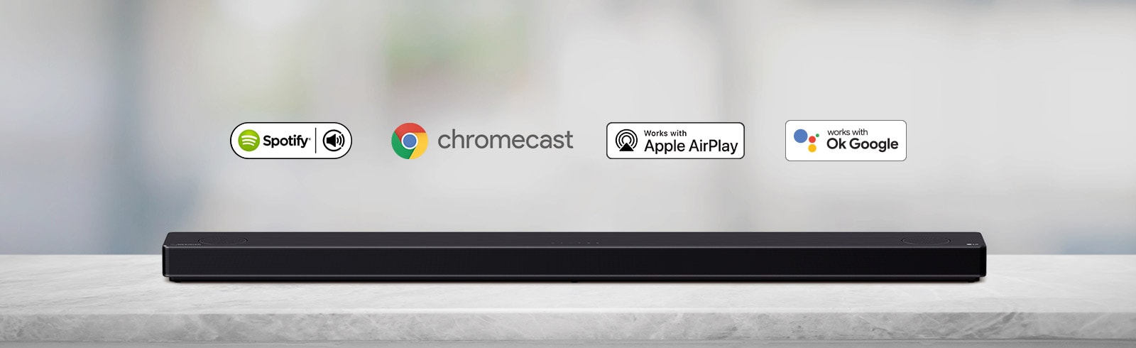 یک ساندبار واقع در قفسه‌ای خاکستری رنگ به همراه لوگوهای پلتفرم هوش مصنوعی (به ترتیب از چپ به راست، اسپاتیفای، الکسا، کروم کست، اپل ایرپلی و اوکی گوگل) مشاهده می‌شود.