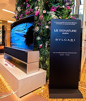 Un cartello sulla collezione LG SIGNATURE e BVLGARI accanto a un TV OLED R arrotolabile. 