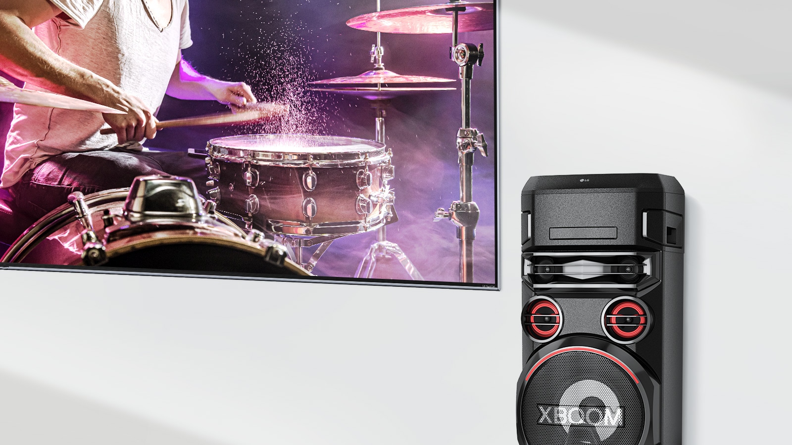 يوجد تلفزيون على الحائط مع LG XBOOM على يمينه.