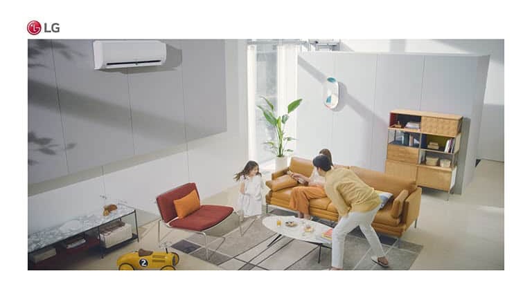 أسرة يمرح أفرادها بغرفة المعيشة مع وجود مكيف الهواء بالجزء العلوي من الصورة.