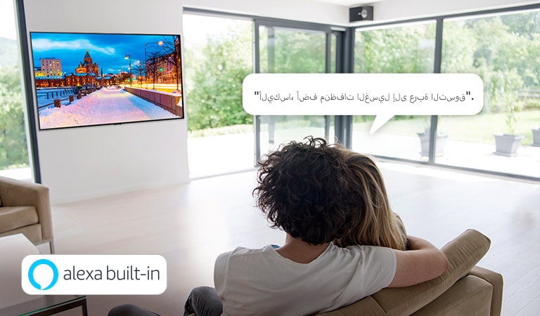 زوجان يجلسان على الأريكة يطلبان من مساعد أمازون اليكسا إضافة منظفات الغسيل إلى عربة التسوق