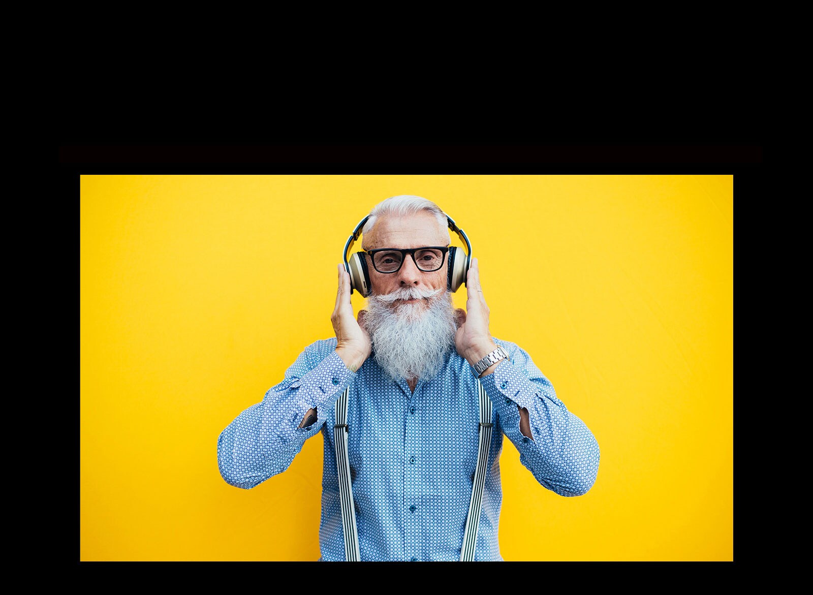 جَد يقف أمام جدار أصفر - يرتدي سماعة رأس.