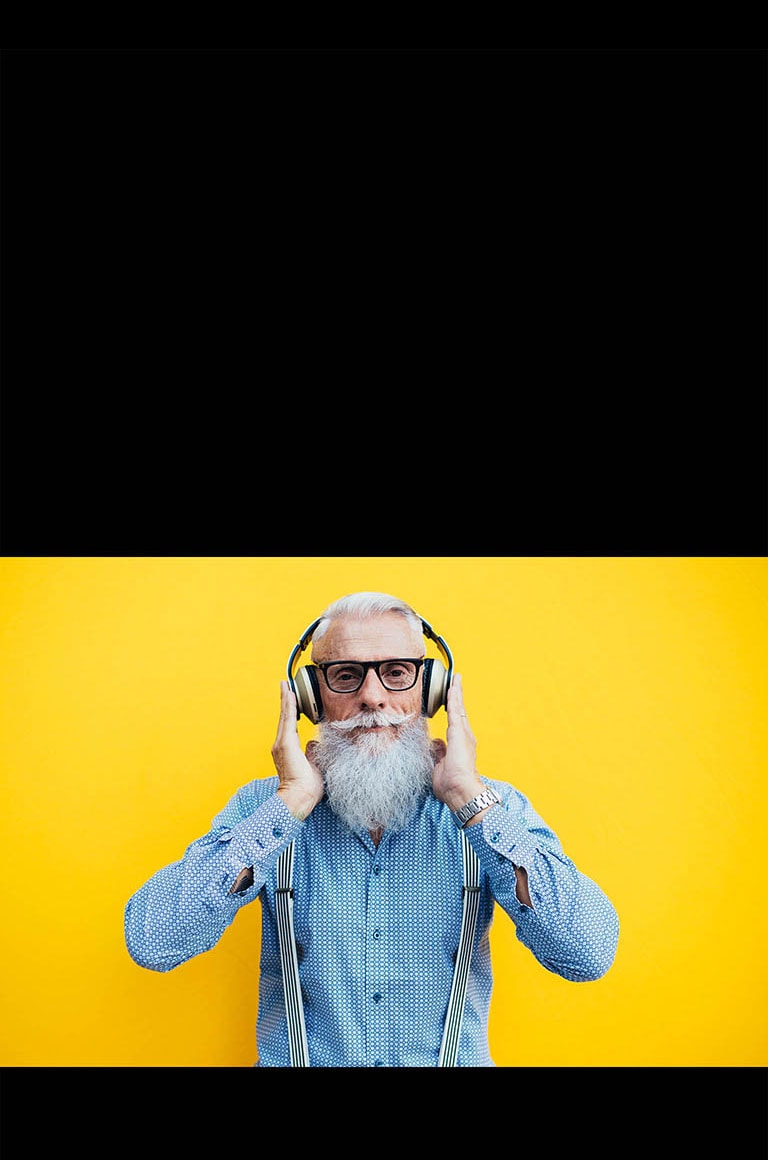 جَد يقف أمام جدار أصفر - يرتدي سماعة رأس.