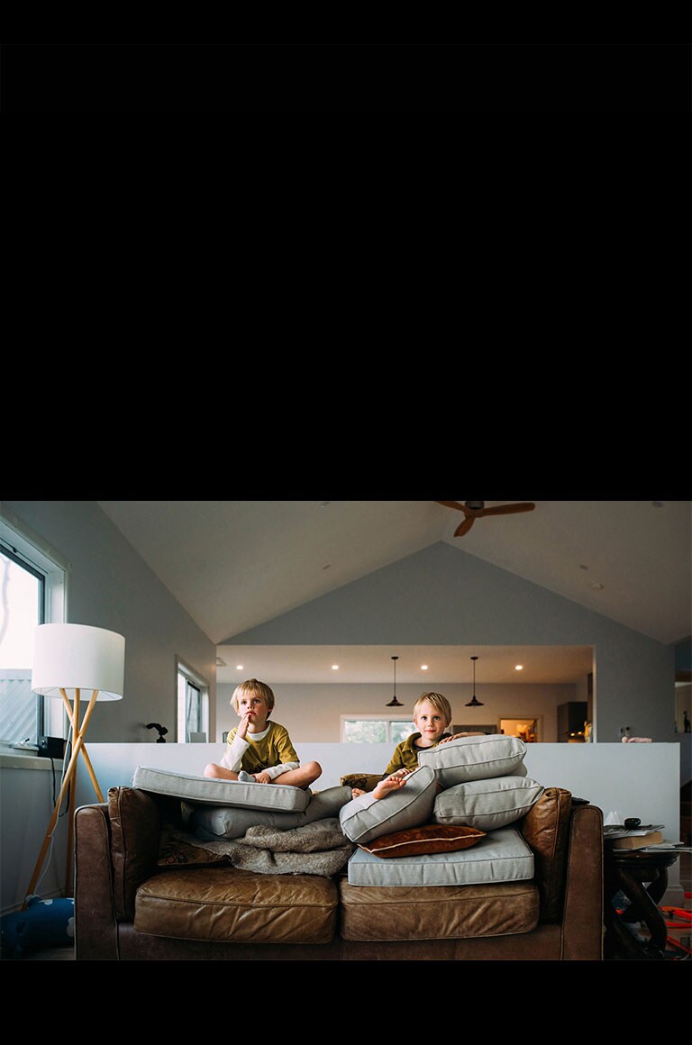 صبيان توأمان يشاهدان شيئًا أثناء جلوسهما على الأريكة.