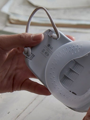 أيدي تمسك بالقناع تظهر الجزء الداخلي شرائط الأذن.