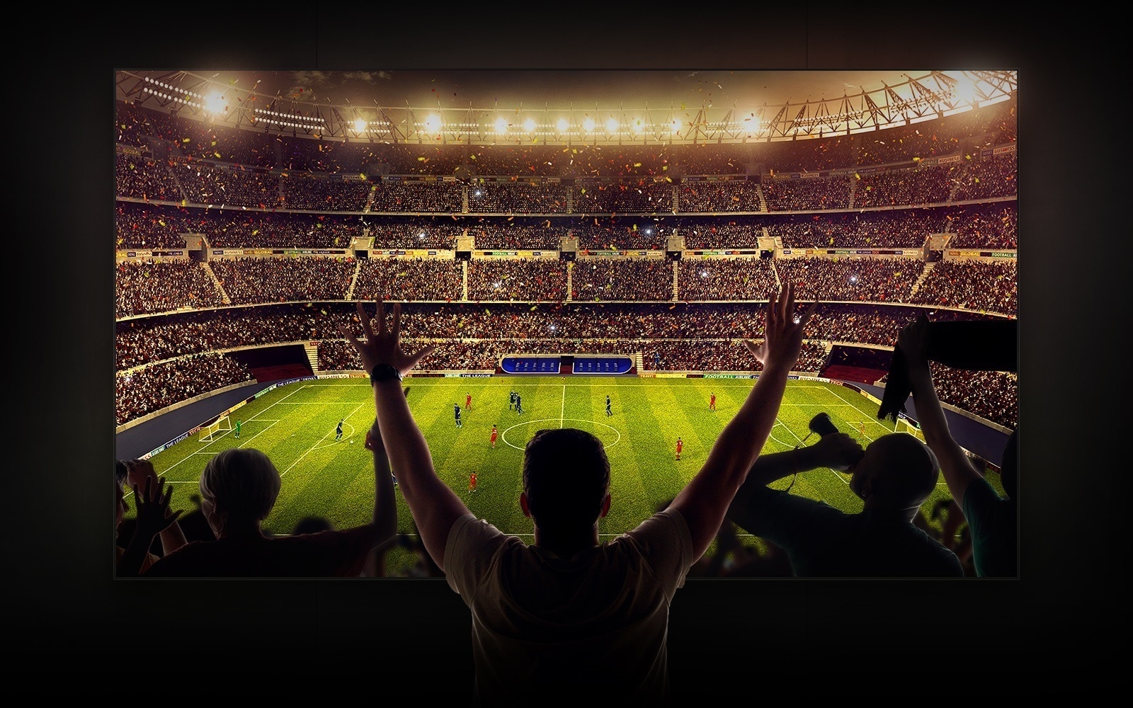 Four people sitting on a couch watching a large screen TV displaying a soccer stadium filled with spectators.