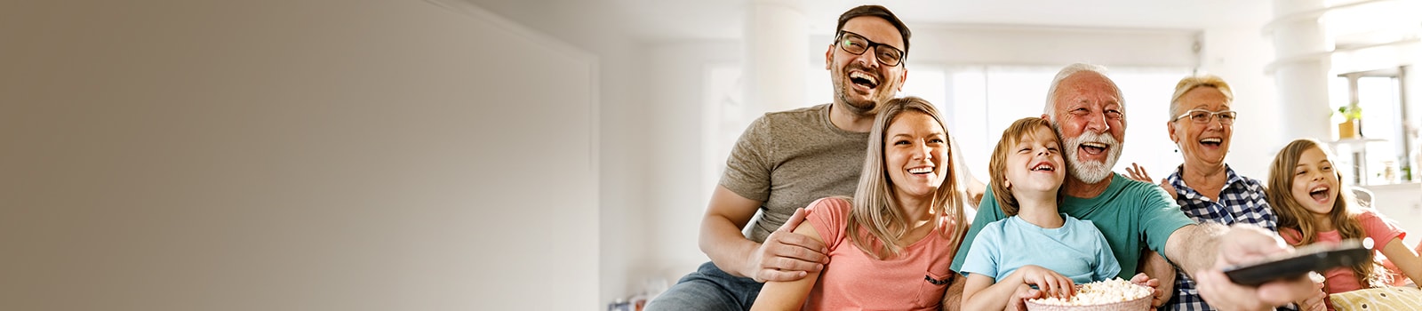 تجلس عائلة بينما يضحكون والجد يوجِّه جهاز التحكم عن بُعد.
