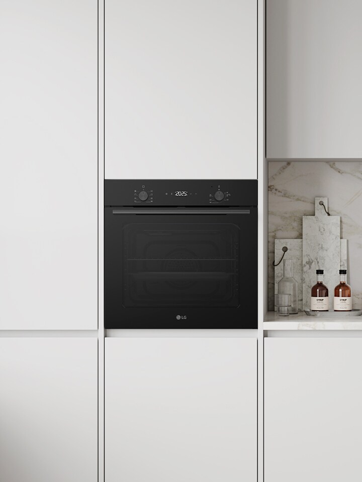 Modern white kitchen with built-in black radiant cooktop, oven, hood, and sink.