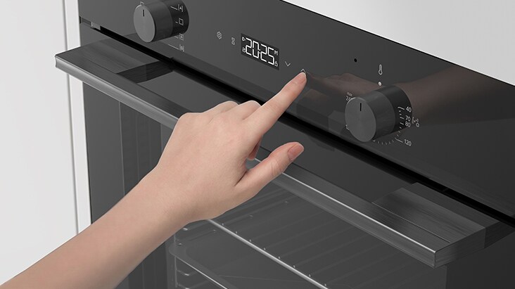 Hand adjusting touch controls on a built-in oven control panel.