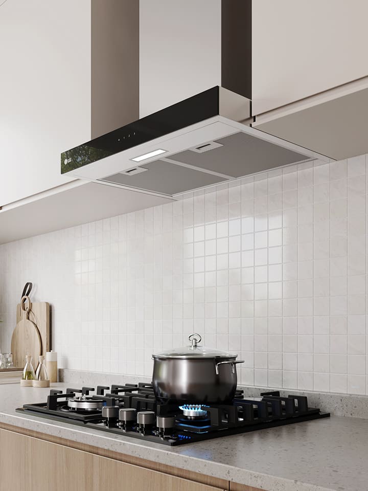Modern kitchen interior featuring a built-in range hood above a gas cooktop with a pot, against a white tile wall.