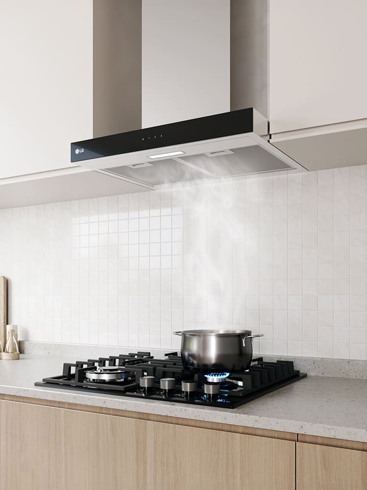 Modern kitchen interior featuring a built-in range hood above a gas cooktop with a pot, against a white tile wall.