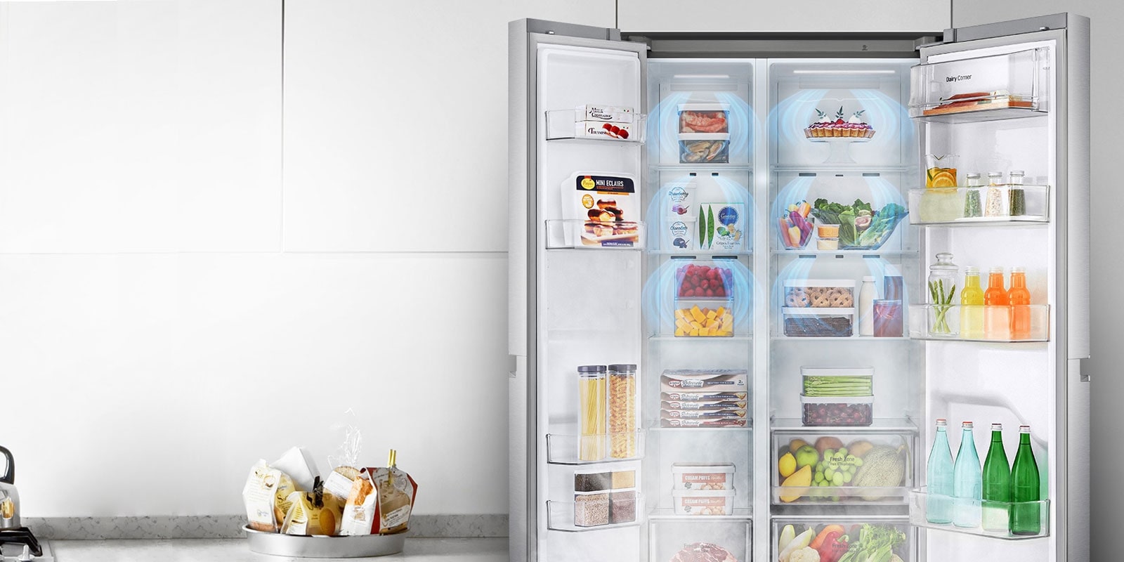 A front view of the refrigerator with the two front doors wide open showing a full stocked fridge. Blue clouds of mist are shown going down over all of the produce.