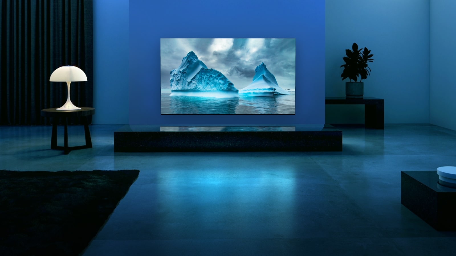 A blue neon circuit moves around on blue glacier image. The camera zooms out and shows this blue glacier within TV screen. The TV is placed in a wide living room with blue background.