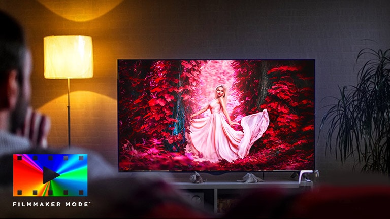 A man sitting on a sofa in the living room with the colorful movie on the TV screen