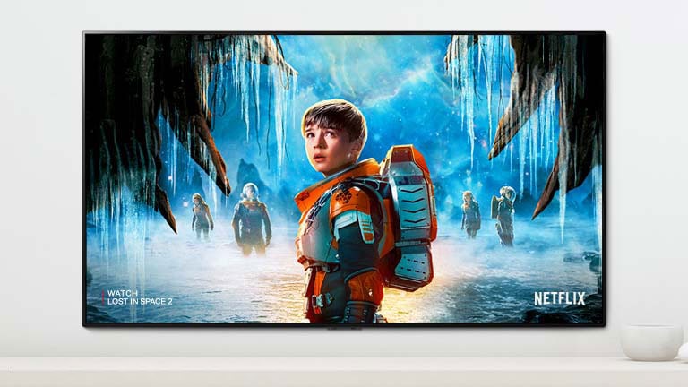 A scene of Lost in Space 2 series showing main characters with an intense look on a TV screen