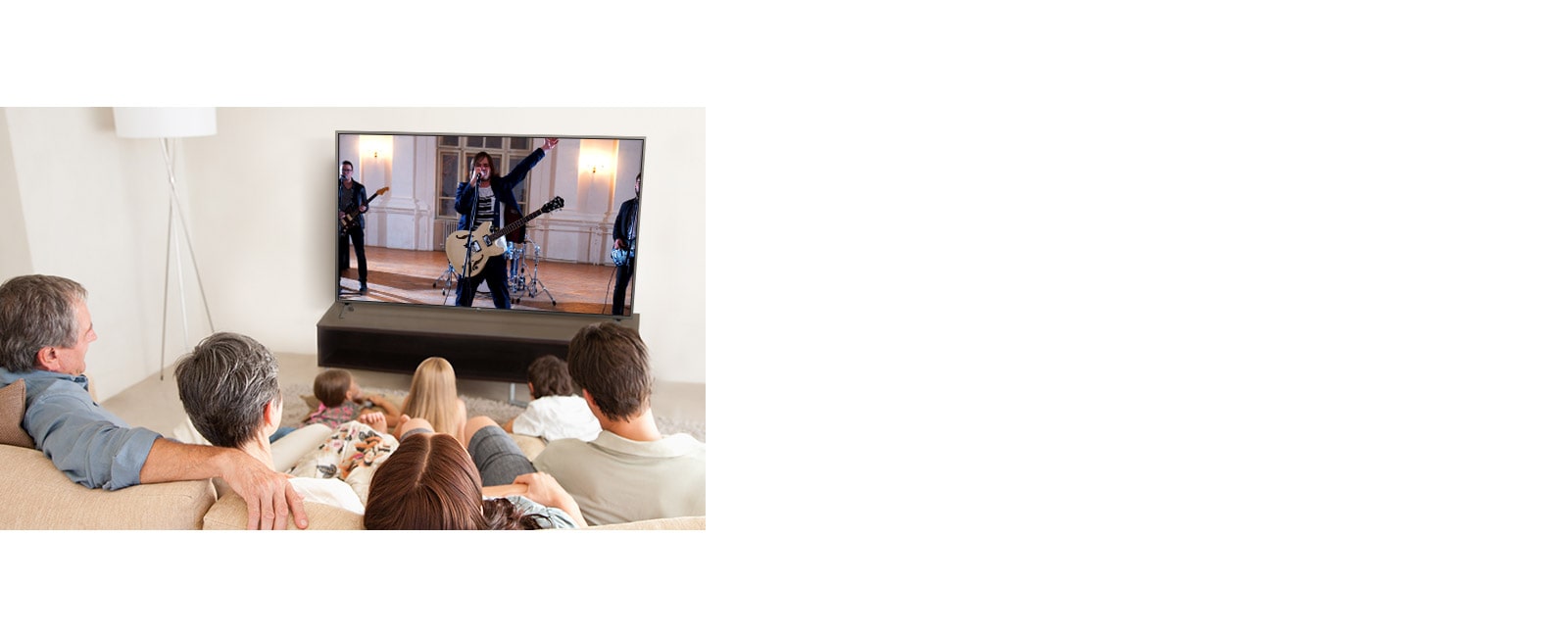 Family of seven gathered in the living room, watching a movie. TV screen shows a band performing.