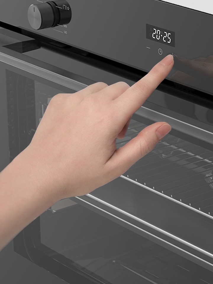 Hand adjusting touch controls on a built-in oven control panel.
