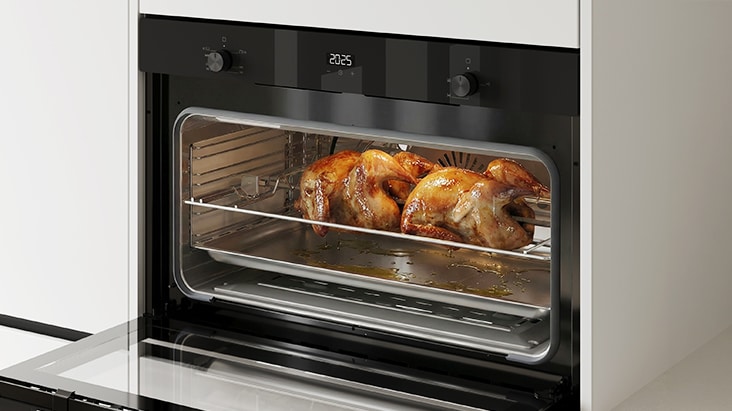 Built-in oven with rotisserie accessory roasting a whole chicken.