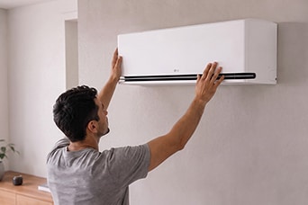 A technician maintaining a wall-mounted air conditioner.