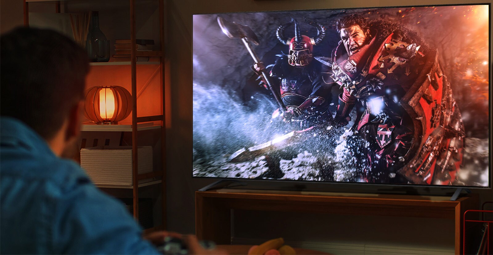 A man sits on a couch in a dark room playing an RPG game on a large TV.