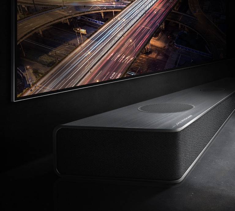 The edge of the soundbar is subtly visible below the TV screen with the night view of the road.