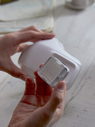 One hand holds a filter and the other holds the mask ready to insert it.