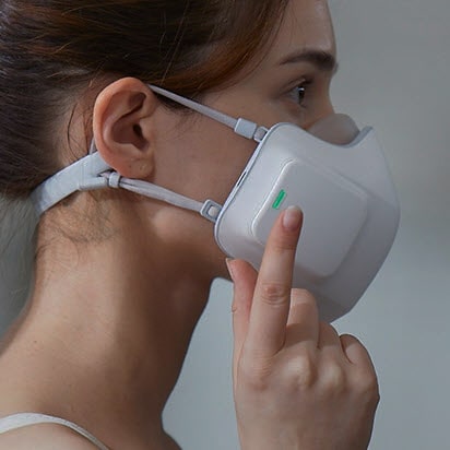 The side view of the wearable air purifier on a woman. Her finger is tapping to turn it on.