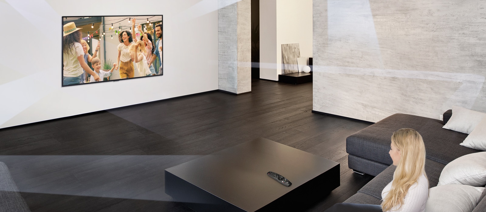 Woman in large and minimalistic living room watching people dancing on TV.