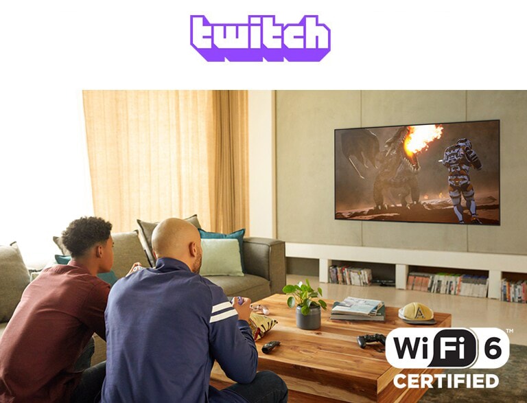 The logo of Google Stadia and Twitch are in a line. Two men sitting on the sofa are playing game with controllers and Wi-Fi 6 certified in a living room.