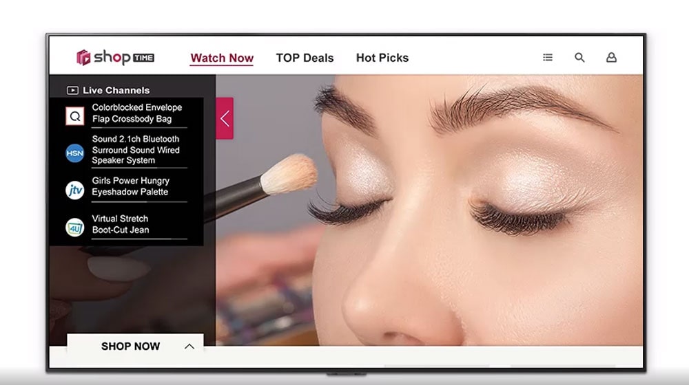 A TV screen of closeup of a woman's face getting make-up, program information to watch, and hot deals to shop.