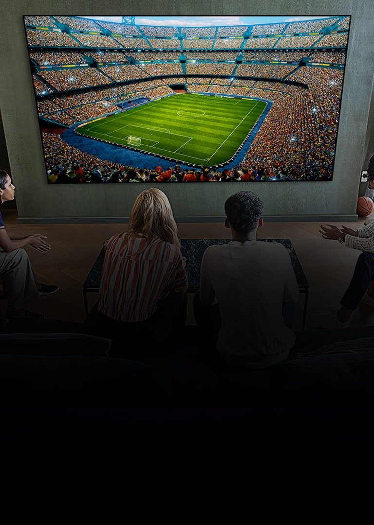 People watching a soccer game on a large TV screen in the living room