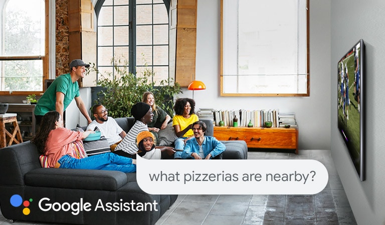 Woman watching football on TV with friends and asking the Google Assistant what pizzerias are nearby