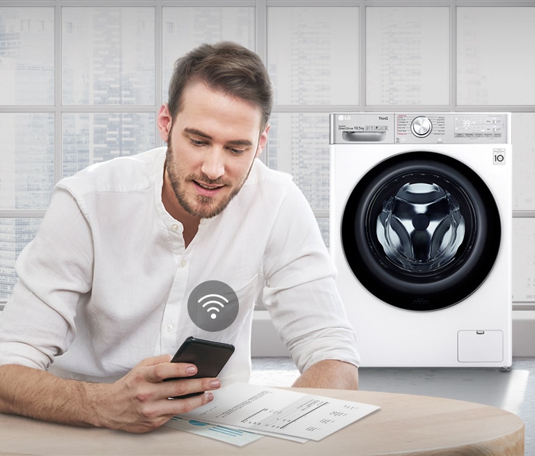 A man is monitoring the condition of the washing machine through a mobile phone app.