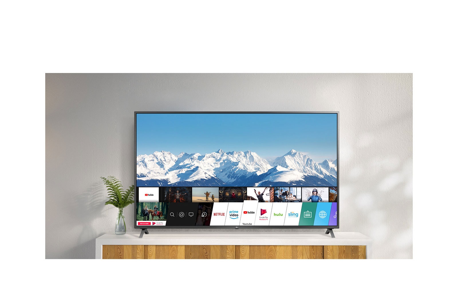 TV standing on a white stand against a white wall. TV screen shows home screen with webOS.