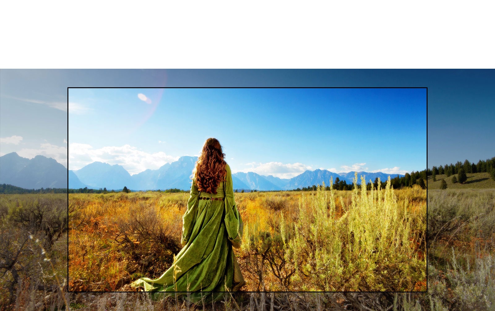 A TV screen showing a scene from a fantasy movie with a woman standing in the fields facing the mountains.