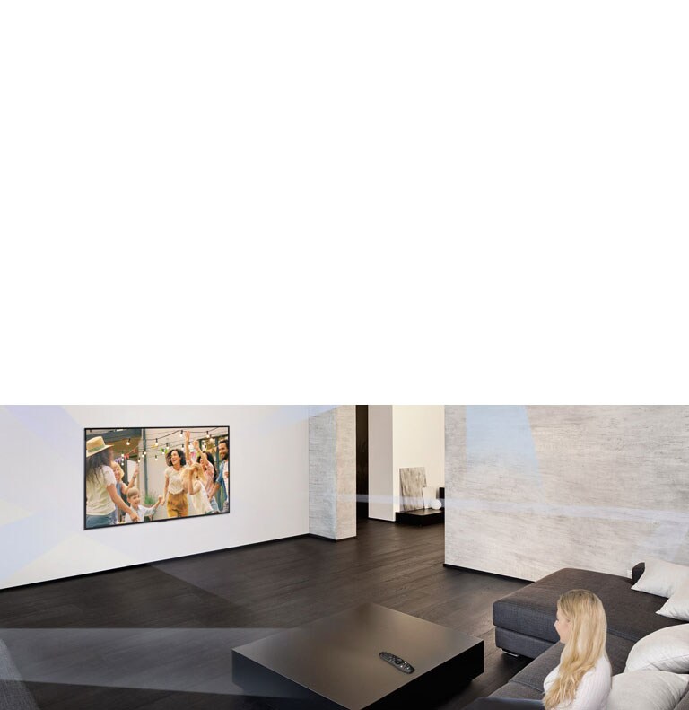 Woman in large and minimalistic living room watching people dancing on TV