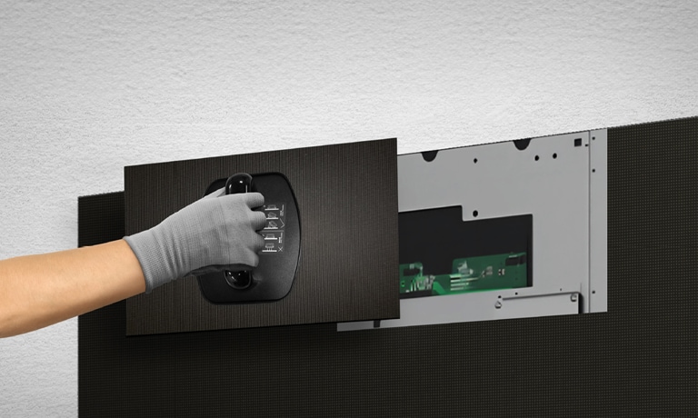 A person replaces one of the LED modules from the front using the provided magnetic tool.