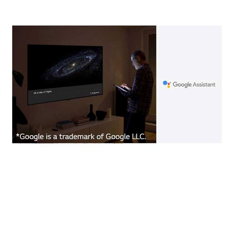 A man is standing in front of TV and ask google assistant to turn off the light