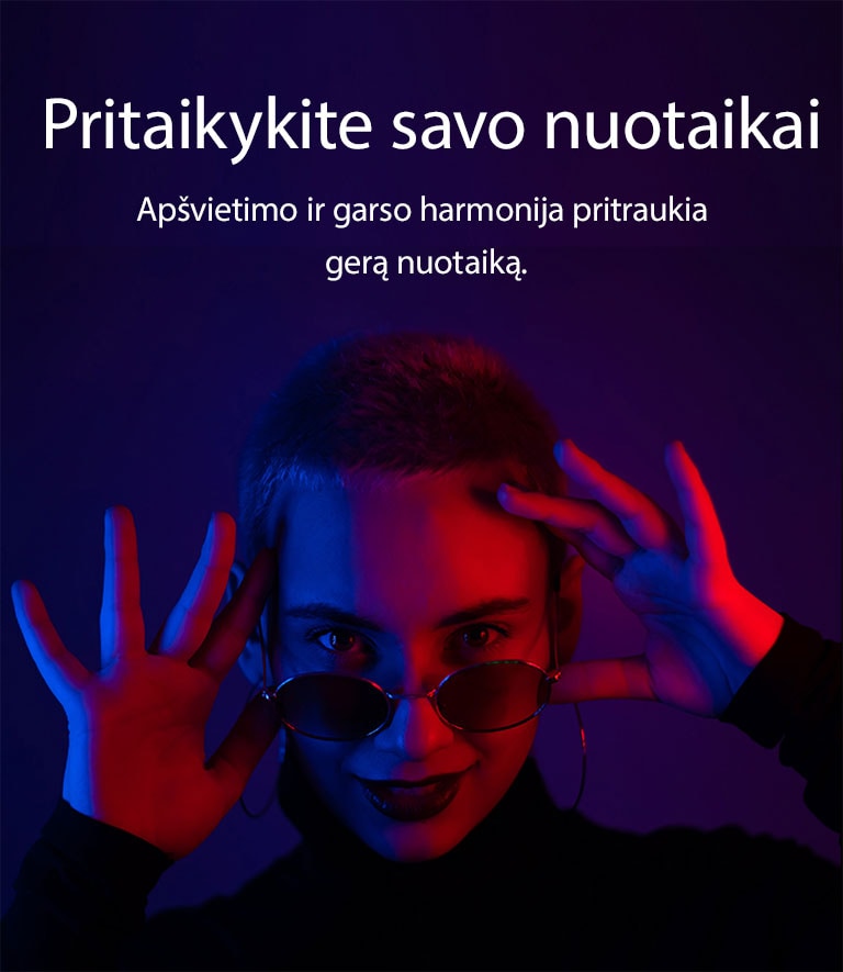 Moteris pozuoja ryškiame apšvietime.