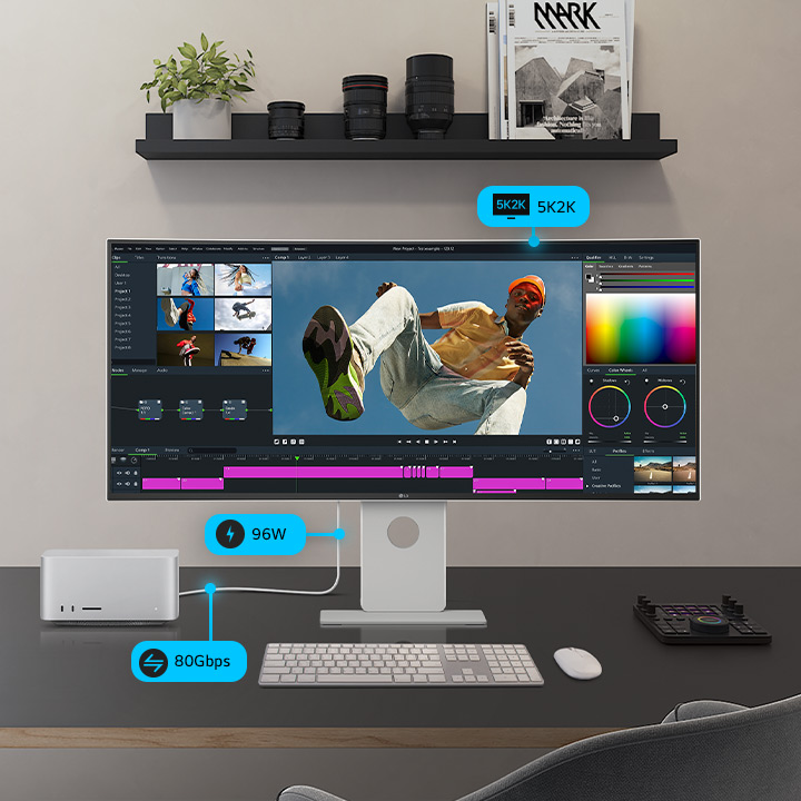 „UltraFine“ monitorius, kuriame matomas programos langas, stovi šalia mažesnio monitoriaus, kompiuterio ir atminties įrenginio, sujungtų laidas; demonstruojama daugiafunkcinė jungtis.