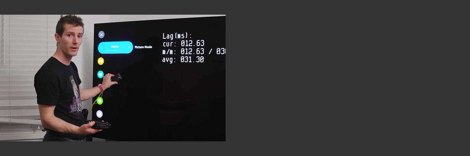 Nuomonės žaidimų srityje formuotojas kanalo „Linus Tech Tips“ vedėjas rodo pateiktį apie LG OLED mažą įvesties delsą priešais LG OLED TV ekraną