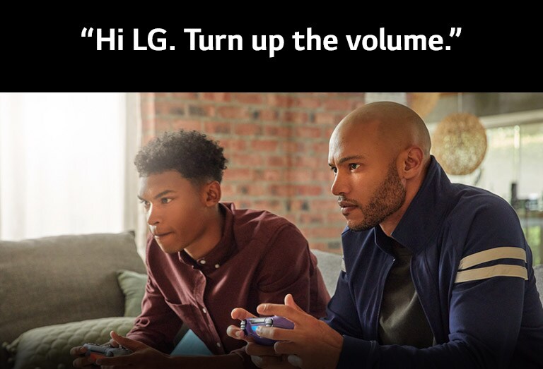 Belaidžius žaidimų valdiklius laikantys ir į žaidimą įsitraukę du vaikinai sėdi ant sofos