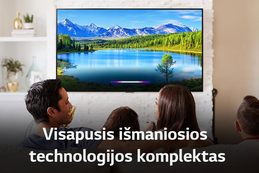 Šviesiame kambaryje šeima žiūrį į kraštovaizdį, rodomą per ant sienos įrengtą TV