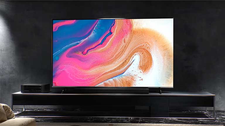 Įrengimo vaizdo įraše rodoma, kaip tamsiame kambaryje ant sienos įrengiamas plonas televizorius.