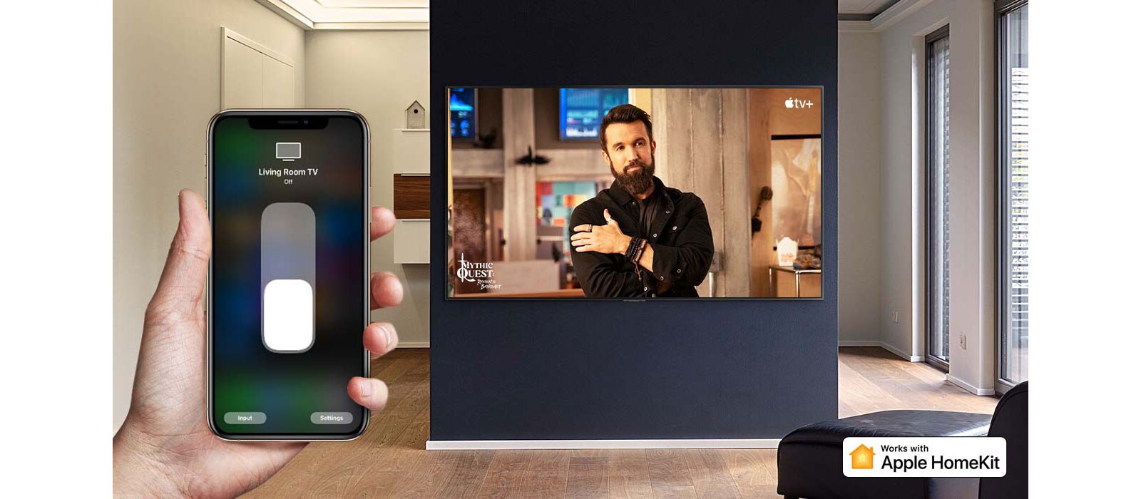 Televizorių „iPhone“ įrenginiu valdanti ranka stambiu planu ir televizorius, kuriame rodomas „Apple TV+“ turinys