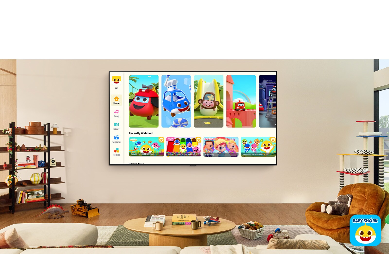 Mažas berniukas žiūri „Pinkfong“ per sieninį LG TV gyvenamojoje erdvėje su vaikiškais žaislais. 