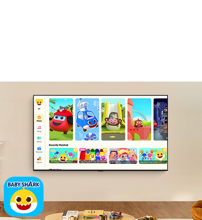 Mažas berniukas žiūri „Pinkfong“ per sieninį LG TV gyvenamojoje erdvėje su vaikiškais žaislais. 