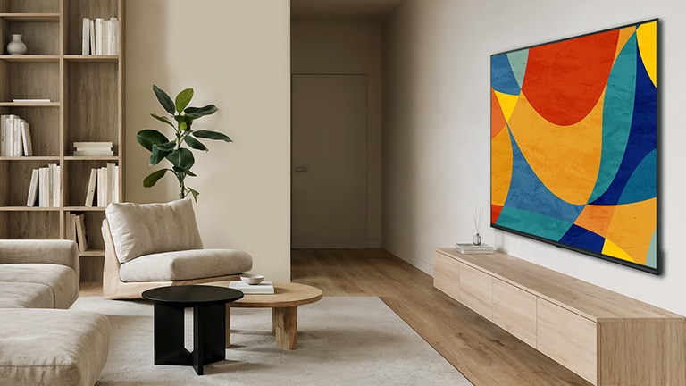Itin plonas LG NANO 4K UHD AI NU80 pritvirtintas prie sienos, šviesioje ir atviroje gyvenamojoje erdvėje, pasižymi elegantišku profiliu, kuris sklandžiai dera interjere; ekranas rodo gyvybingas, daugiaspalves ir abstrakčias figūras.