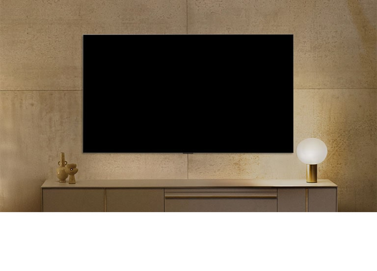 LG NANO 4K UHD AI NU80 ant sienos su išjungtu ekranu, kuris įsijungia, kai žmogus prieina arčiau – suveikia judesio jutiklis ir rodomas abstraktaus sūkurio meno kūrinys. 